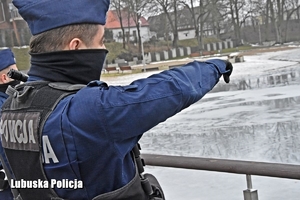policjant wskazuje na zamarznięte jezioro