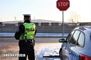 Policjant drogówki stojący przy drodze.
