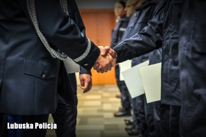 Komendant Wojewódzki Policji podaje rękę nowo przyjętemu policjantowi.