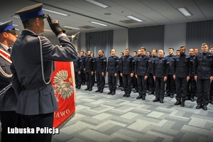 Poczet sztandarowy na tle nowo przyjętych policjantów.