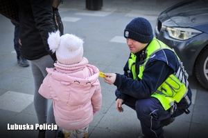 Policjant przekazuje odblaski dziecku