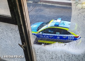 Policyjny radiowóz widziany z okna opuszczonego budynku.