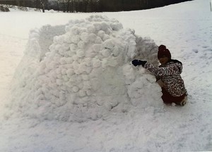 Dziewczynka buduje domek ze śniegu