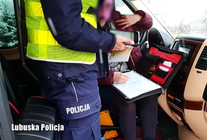 Policjant dokonujący kontroli dokumentacyjnej autokaru