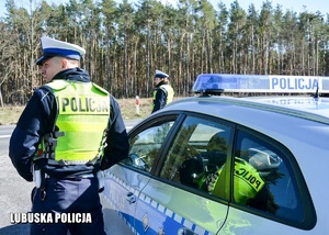 Policjant drogówki stojący przy radiowozie.