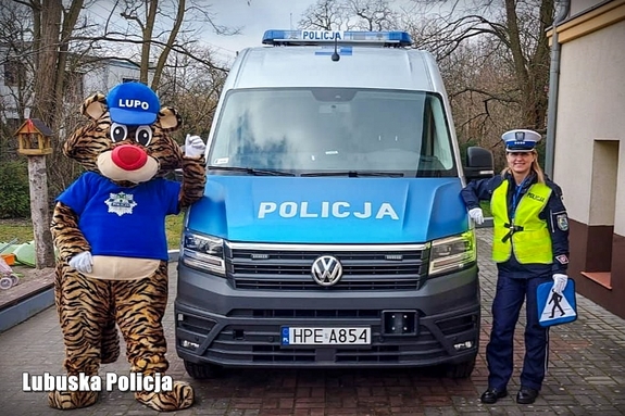 Policjantka i policyjna maskotka przy radiowozie