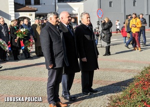 Wojewoda Lubuski wraz dwoma innym mężczyznami oddają hołd przed pomnikiem.
