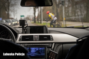 policjanci jadąc radiowozem ustępują pierwszeństwa rowerzyście