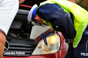 Policjant ruchu drogowego kontroluje stan techniczny samochodu