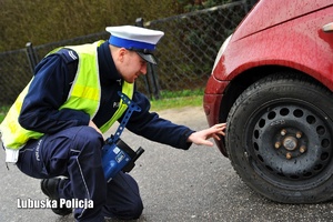 Policjant uchu drogowego kontroluje stan opon