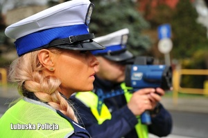 Policjant z miernikiem prędkości. Obok policjantka ruchu drogowego