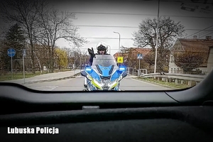Policjant na motocyklu zatrzymuje pojazd do kontroli drogowej.