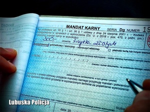 Policjant wypisuje blankiet mandaty karnego