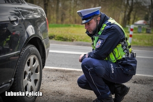Policjant ruchu drogowego sprawdzający stan opon kontrolowanego auta