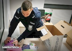 Policjant pakuje prezenty do kartonów.