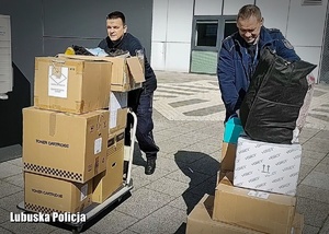Policjanci przewożą zapakowane kartony z prezentami.