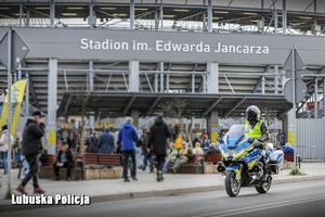 policjant na motocyklu jedzie obok stadionu