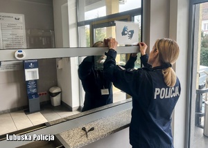 Policjantka nakleja kartkę z symbolem dla osób ze szczególnymi potrzebami.