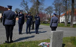Policjanci oddają honory przed pomnikiem.