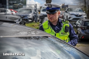 Policjant drogówki stojący przy kontrolowanym pojeździe.