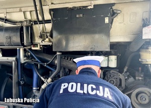 Policjant sprawdza stan techniczny autokaru.