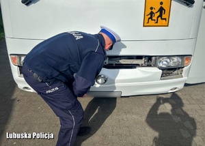 Policjant sprawdza stan techniczny autokaru.