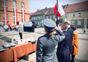 Policjantka oraz pozostałe osoby podczas podniesienia flagi Polski.