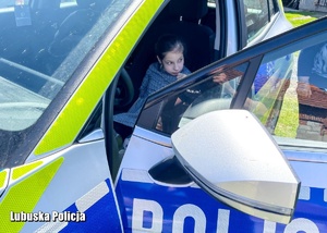 Dziewczynka siedząca w radiowozie policyjnym.