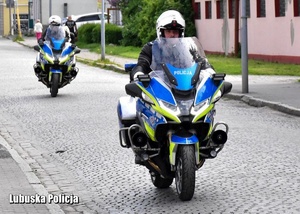 Policyjni motocykliści jadący jezdnią.