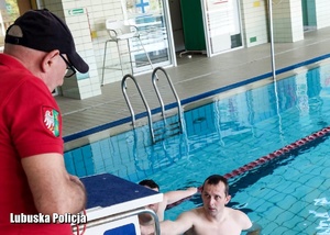 Ratownik wodny podczas rozmowy z mężczyzna znajdującym się w basenie.