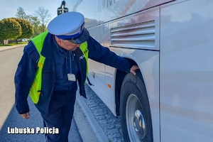 policjant sprawdza stan ogumienia autokaru