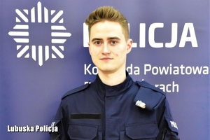 policjant stoi przed banerem komendy w Żarach