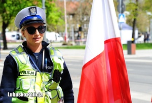 Policjantka drogówki stojąca przy fladze Polski.