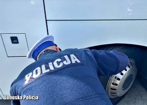 policjant kontroluje stan ogumienia autokaru