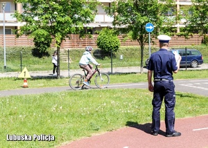 Policjant drogówki ocenia jazdę rowerzystki na drodze.