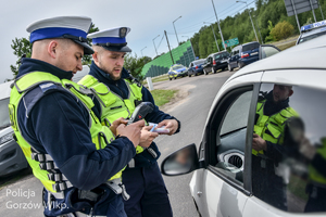 Policjanci drogówki podczas legitymowania kierowcy zatrzymanego do kontroli drogowej.