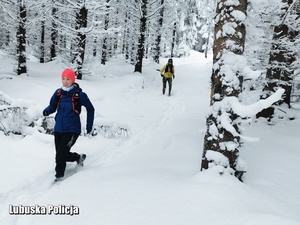 Kobieta podczas biegu w lesie w zimowych warunkach.