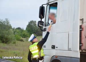 Policjant drogówki kontroluje kierowcę ciężarówki.