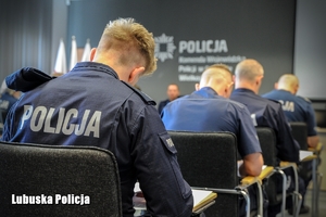 Policjanci siedzący w sali konferencyjnej podczas pisania testu.