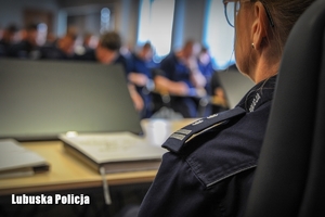 Policjantka, a w tle inni policjanci siedzący w sali konferencyjnej podczas pisania testu.