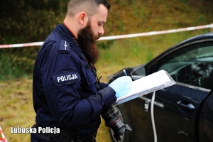 Policjant podczas przeprowadzania i sporządzania protokołu oględzin.