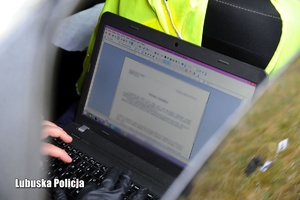 Policjant pracujący na komputerze podczas sporządzania protokołu oględzin.