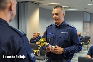 policjant wręcza nagrodę innemu policjantowi