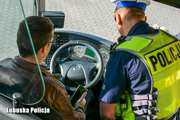 policjant kontroluje kierowcę i autokar