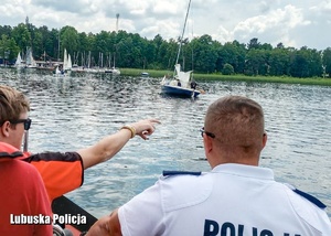 Policjant i ratownik wodny na motorówce podczas patrolu nad jeziorem.