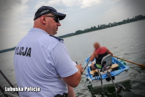 Policjant patrolu wodnego na łodzi obserwuje zachowania osoby na jednostce pływającej