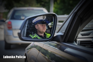 Policjant ruchu drogowego widziany w lusterku auta