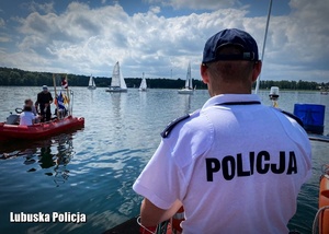 Policjant podczas patrolu  - w tle łódka nad wodą.