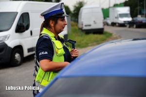 Policjantka drogówki stojąca przy kontrolowanym pojeździe.