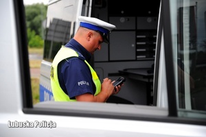 Policjant podczas sprawdzania danych kierującego w systemie.